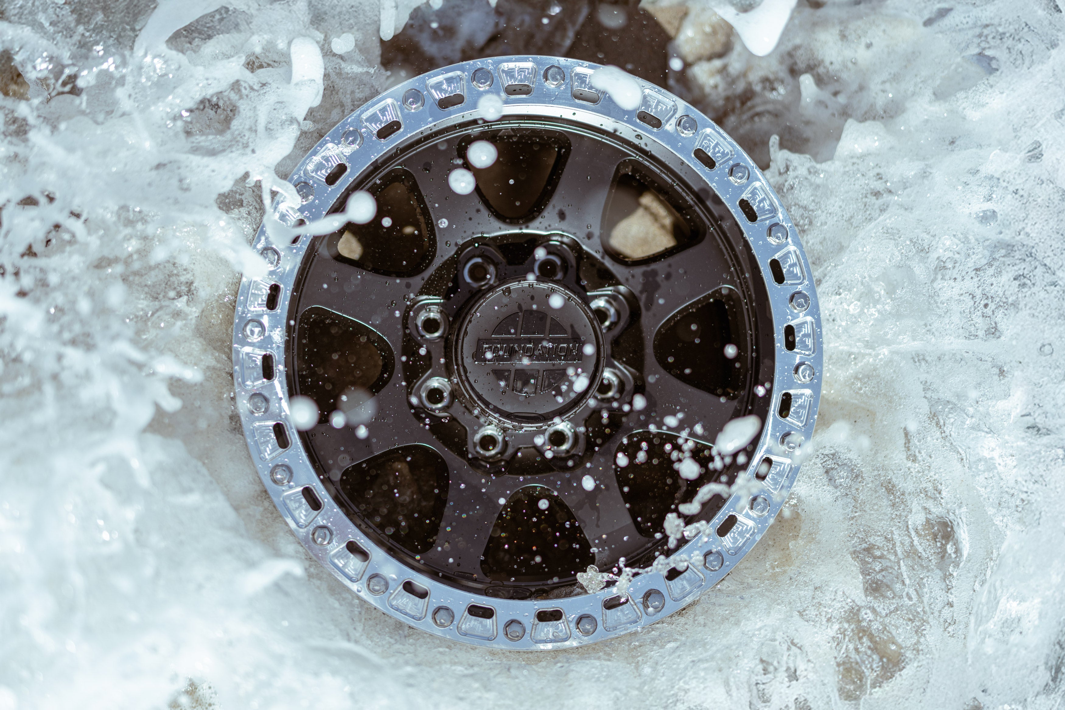 Water splashing around a black 8 lug flow formed wheel with a silver rim
