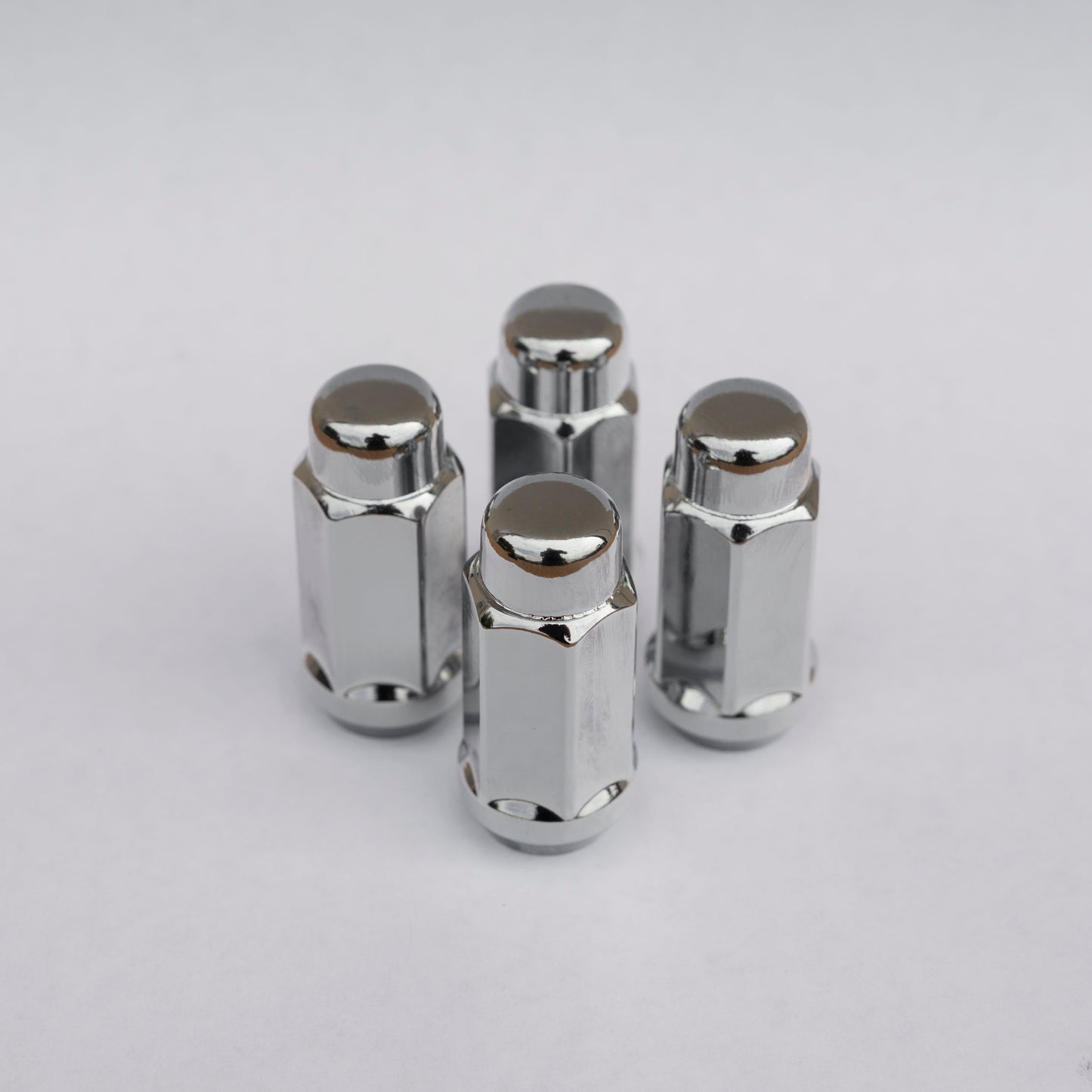 Four chrome metal close top lug nuts for RAM 2500/3500 HD trucks on a light gray background
